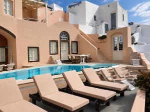a villa with a swimming pool and lounge chairs at Grand Canava in Oia