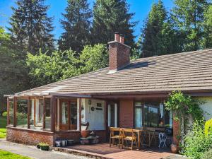 a brick house with a deck with tables and chairs at Smiddy Cottage in Alyth