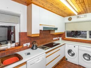a kitchen with a sink and a washing machine at Smiddy Cottage in Alyth +10 photos