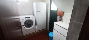 a small kitchen with a washing machine and a refrigerator at Ilhéus à vista in Feteira