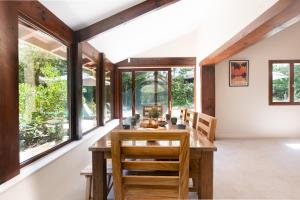 a dining room with a table and chairs and windows at Villa Igelak - Hossegor - Centre - Lac - Piscine in Soorts-Hossegor