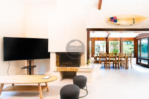 a living room with a fireplace and a surfboard on the wall at Villa Igelak - Hossegor - Centre - Lac - Piscine in Soorts-Hossegor