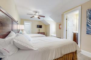 a bedroom with a large white bed with a ceiling fan at Hola Beaches in Corolla +46 photos