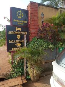 a sign for a garden guest hotel with plants at Golden Quest Hotel in Entebbe