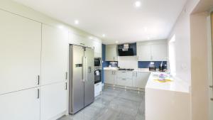 a kitchen with white cabinets and a refrigerator at Firsbrook House - Wark Northumberland in Wark