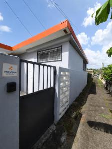 a white house with a black gate and a driveway at URBAN LOFT- Espace détente in Fort-de-France