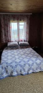 a bed with a blue and white comforter and a window at Macanovic Country House in Glibaći