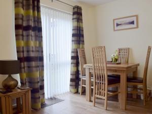 a dining room with a table and chairs and curtains at 18 Elm Court in Keswick