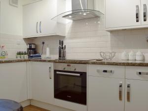 a kitchen with white cabinets and a stove top oven at 18 Elm Court in Keswick
