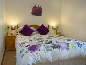 a bedroom with a large bed with purple pillows at 18 Elm Court in Keswick