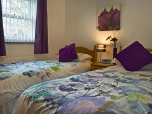 a bedroom with two beds with purple pillows at 18 Elm Court in Keswick +3 photos