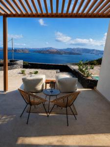 a patio with two chairs and a table with a view at Vespera Private Luxury Suites in Santorini +38 photos