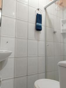 a white tiled bathroom with a toilet and a sink at Origem Bahía in Salvador