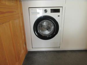 a washing machine in a room with a wooden cabinet at Taighali Apartment in Aultbea