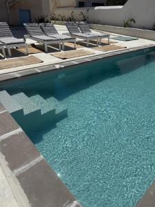 a swimming pool with chairs and blue water at Tinion Hotel in Tinos