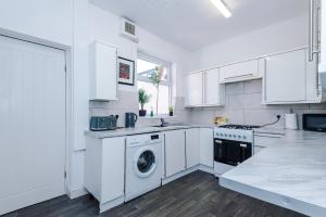a kitchen with white cabinets and a washer and dryer at Stylish 2-Bed House Sleeps 4 in Saint Helens