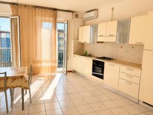 a kitchen with white cabinets and a table and a dining room at De Amicis Sea Home in Gabicce Mare +16 photos
