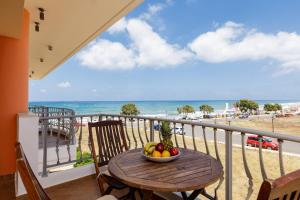 a table with a bowl of fruit on a balcony with the beach at Kahlua Bay Apartments in Hersonissos