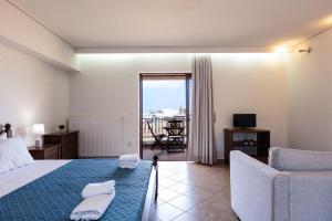 a bedroom with a bed and a couch and a balcony at Kahlua Bay Apartments in Hersonissos