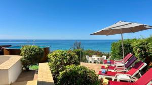 a patio with chairs and an umbrella and the ocean at Beira Mar - Private Pool - 7 Guests - Albufeira in Albufeira