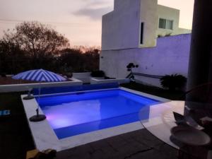 a blue swimming pool with an umbrella on a patio at Casa Tikul in Temixco