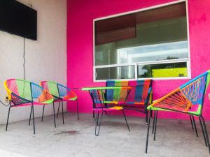 a colorful table and chairs in front of a pink wall at Casa Tikul in Temixco