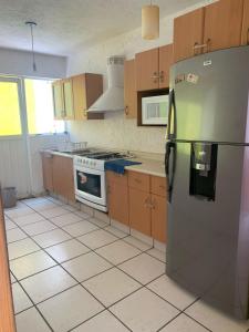 a kitchen with a stainless steel refrigerator and wooden cabinets at Casa Tikul in Temixco