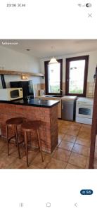 a kitchen with a counter and two stools in it at Gîte teyssonniere in Usson-en-Forez