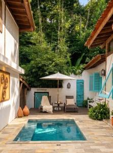 a swimming pool with an umbrella and a patio at Zeisa House in Maresias