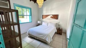 a bedroom with a white bed and a window at Zeisa House in Maresias