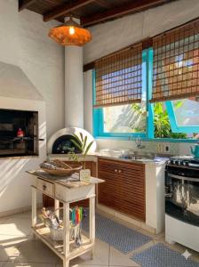 a kitchen with a table and a sink and a stove at Zeisa House in Maresias +8 photos