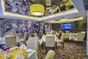 ein Restaurant mit weißen Tischen und Stühlen und einem Fernseher in der Unterkunft Grace21 Runway Hotel in Dhaka