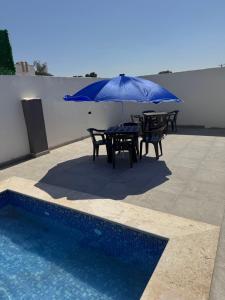 a table with a blue umbrella next to a pool at Venice Private Retreat Tripoli, Libya in Tripoli
