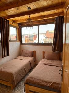two beds in a room with two windows at Blue Drift in Imsouane
