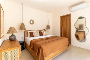 a bedroom with a large bed and a mirror at Villa Candi - Stylish Tropical Pool Villa in Ungasan