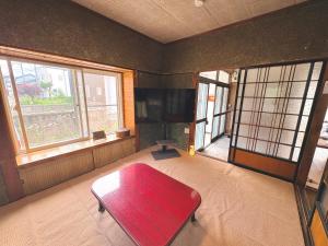 a room with a red bench in a room with windows at 長峰駅から徒歩3分ゲストハウスオオワニ in Ōwani
