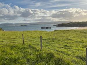 a fence in a field next to a body of water at Taighali Apartment in Aultbea