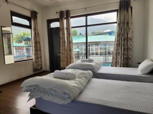 drei Betten in einem Zimmer mit großem Fenster in der Unterkunft Draft Hotel Bir Billing At Landing Site in Bir