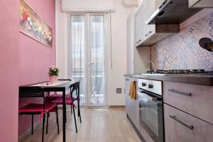 a kitchen with pink walls and a table with chairs at La Casetta di G&G in Varese