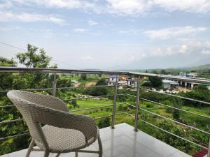 Ein Rattanstuhl auf einem Balkon mit Aussicht in der Unterkunft Draft Hotel Bir Billing At Landing Site in Bir