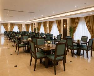 a dining room with tables and chairs and curtains at Zaha Al Madina Hotel in Medina