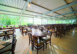 a dining room with tables and chairs in a building at Itapura Eco Resort in Atibaia