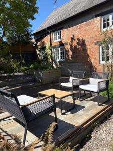 three benches on a wooden deck in front of a brick building at The Cottage in Sulgrave