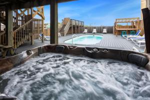 a hot tub on a deck next to a swimming pool at 7000 - Serenity Sands in Whalebone