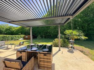 a pergola with a table and chairs under it at La Parenthèse de Quantilly in Quantilly