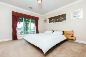 a white bedroom with a large bed and windows at La Bella Vita in Batesford