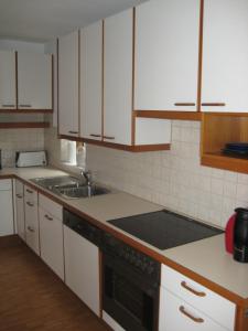 a kitchen with white cabinets and a sink at Ferienhaus Stemer Montafon in Schruns +6 photos