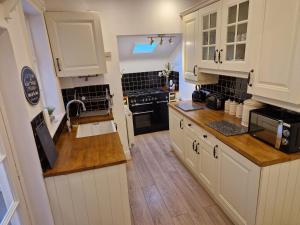 a kitchen with white cabinets and a wooden floor at No22 Chester Racecourse Townhouse in Chester