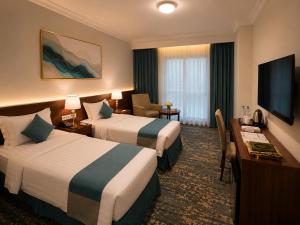 a hotel room with two beds and a desk at Zaha Al Madina Hotel in Medina +22 photos