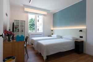 a bedroom with two beds and a desk and a window at Bed & Bricks in Reggio Emilia